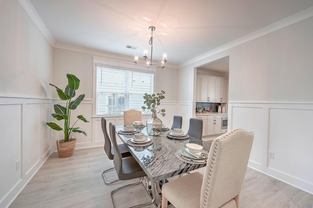 dining room featuring a notable chandelier, ornamental molding, and light wood-type flooring