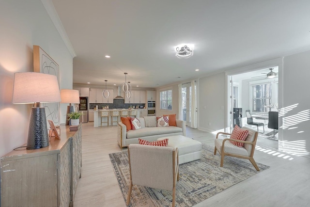 living room with light hardwood / wood-style floors, crown molding, and ceiling fan