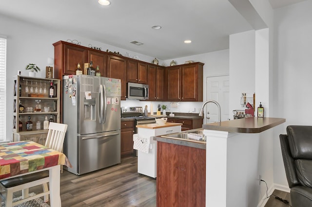 kitchen with visible vents, a peninsula, recessed lighting, dark wood-style flooring, and stainless steel appliances