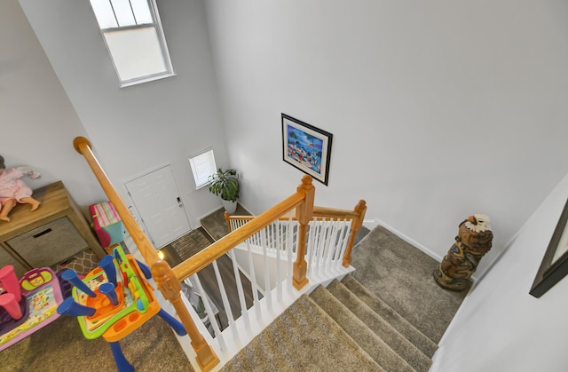 staircase featuring a high ceiling, carpet, and baseboards