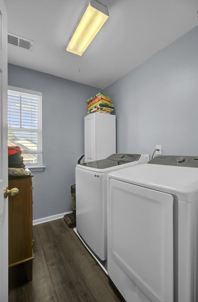 clothes washing area with visible vents, baseboards, laundry area, dark wood-type flooring, and washer and dryer