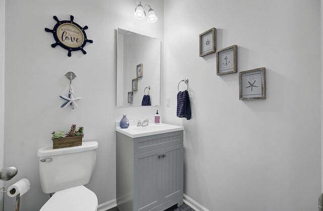 half bath with toilet, vanity, and baseboards