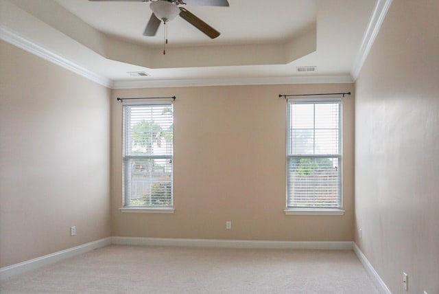 unfurnished room with crown molding, light colored carpet, and a tray ceiling