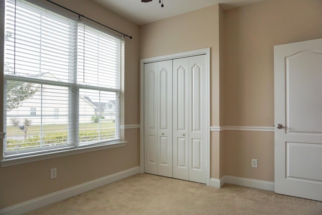 unfurnished bedroom with light carpet and a closet