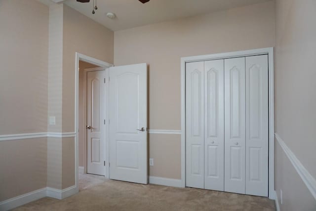 unfurnished bedroom featuring ceiling fan, a closet, and light carpet