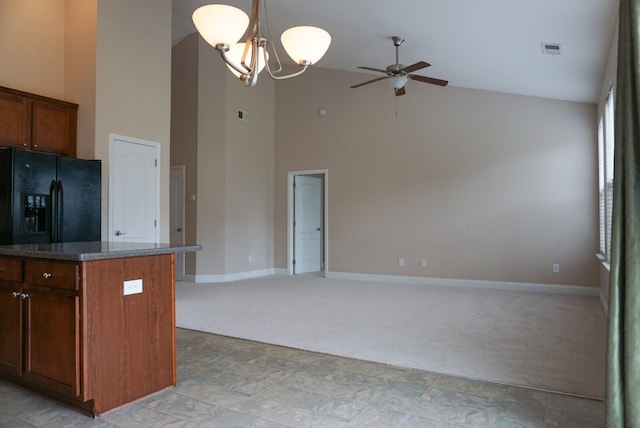 kitchen featuring hanging light fixtures, a center island, black fridge, light carpet, and ceiling fan with notable chandelier