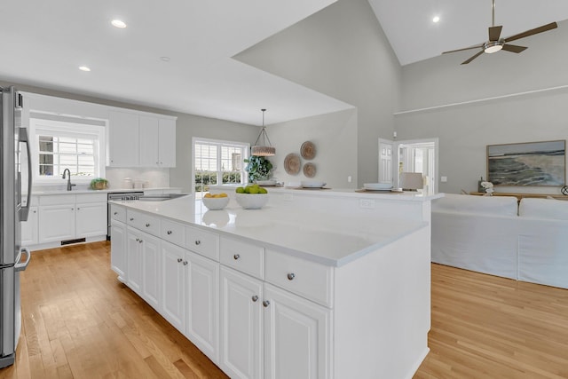 kitchen featuring white cabinetry, appliances with stainless steel finishes, a kitchen island, pendant lighting, and light hardwood / wood-style floors