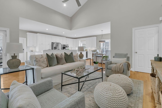 living room featuring ceiling fan, high vaulted ceiling, and light hardwood / wood-style floors