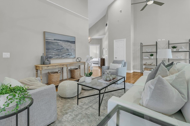 living room with ceiling fan, high vaulted ceiling, and light hardwood / wood-style flooring