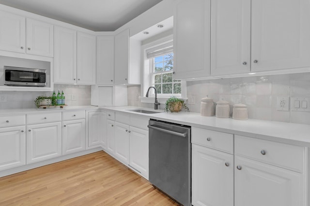 kitchen featuring tasteful backsplash, white cabinetry, sink, light hardwood / wood-style floors, and stainless steel appliances