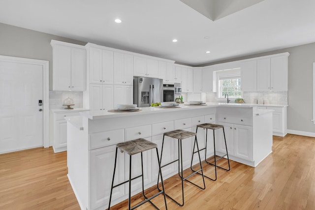 kitchen featuring a kitchen island, a kitchen breakfast bar, white cabinets, and appliances with stainless steel finishes