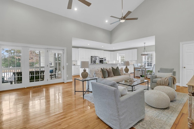 living room featuring a high ceiling, ceiling fan, a wealth of natural light, and light wood-type flooring