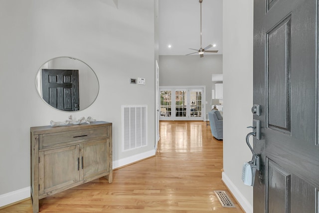 foyer entrance featuring light wood-type flooring, ceiling fan, and a high ceiling