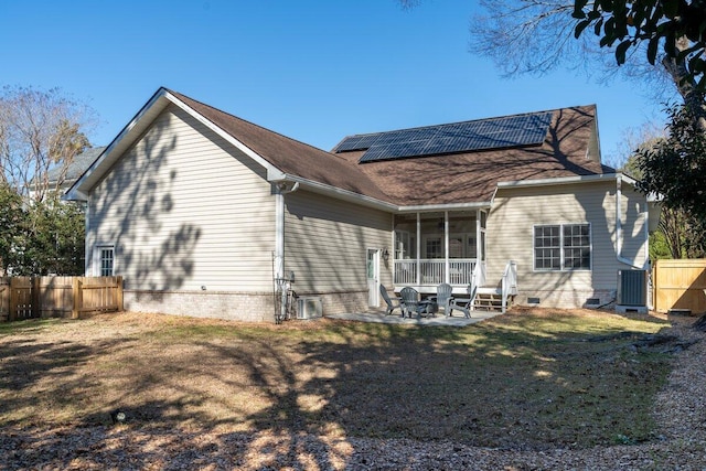 back of house with a patio, a yard, a sunroom, and solar panels