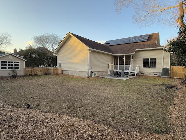 back of property with an outbuilding, cooling unit, a patio area, and solar panels