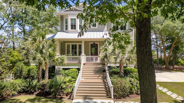 raised beach house with stairs, a porch, and metal roof