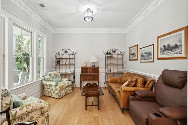 living area with crown molding, light wood-style floors, and wainscoting
