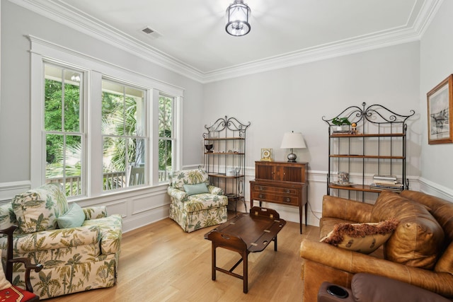 living room featuring wood finished floors, crown molding, and a wainscoted wall