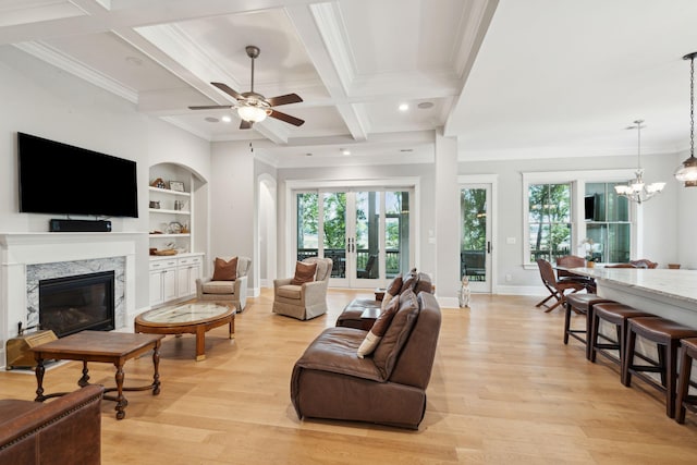 living area featuring crown molding, light wood-style flooring, a fireplace, baseboards, and ceiling fan