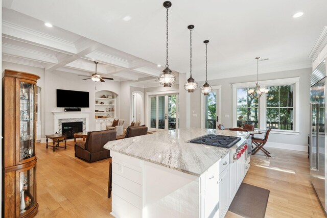 kitchen with a premium fireplace, light wood finished floors, beamed ceiling, appliances with stainless steel finishes, and a ceiling fan