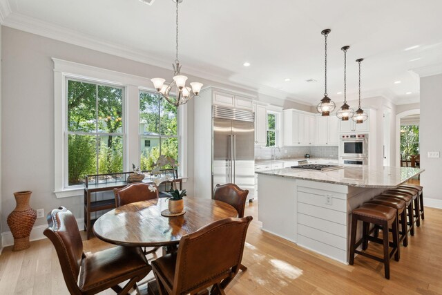 dining area featuring healthy amount of natural light, recessed lighting, crown molding, light wood-type flooring, and a chandelier