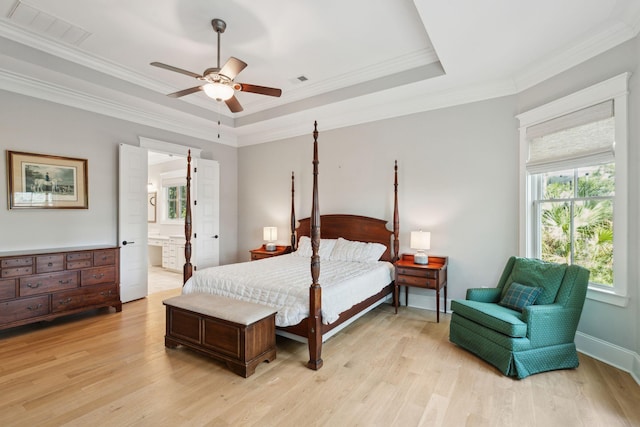 bedroom featuring light wood-type flooring, ornamental molding, a tray ceiling, a ceiling fan, and baseboards
