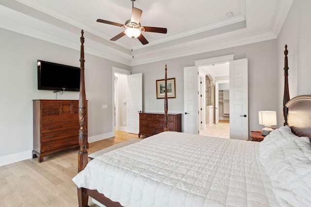 bedroom featuring light wood-style flooring, crown molding, baseboards, a raised ceiling, and a ceiling fan