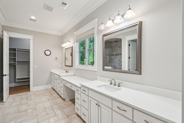 bathroom with ornamental molding, two vanities, tiled shower, baseboards, and recessed lighting