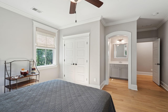 bedroom featuring light wood-style flooring, crown molding, arched walkways, a ceiling fan, and baseboards