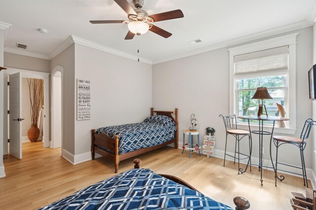 bedroom with wood finished floors, ornamental molding, baseboards, arched walkways, and ceiling fan
