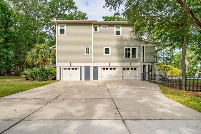 back of house with a garage, concrete driveway, and fence