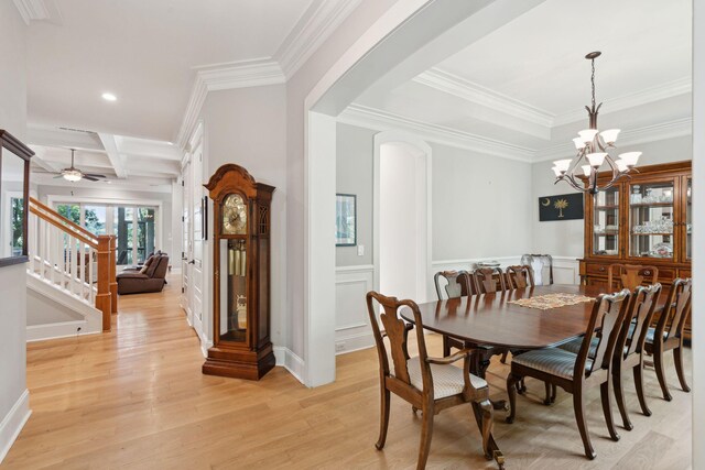 dining space with arched walkways, light wood-style flooring, crown molding, a chandelier, and stairs