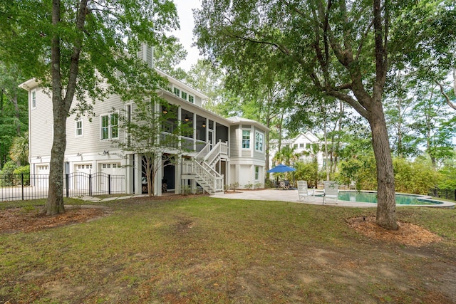 rear view of property with an attached garage, stairs, a sunroom, a chimney, and a ceiling fan