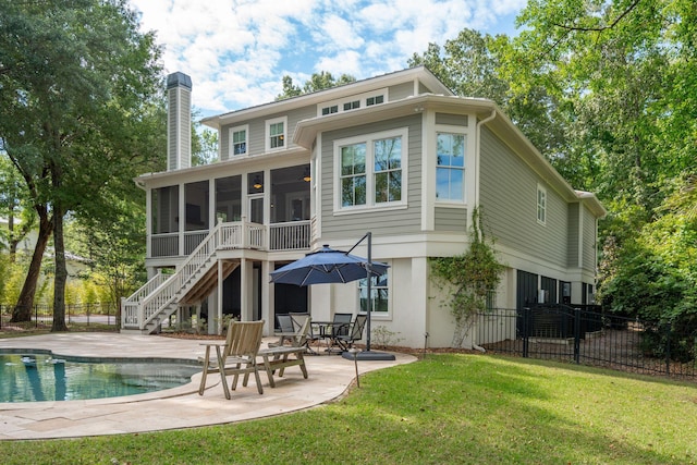 back of property with a sunroom, a chimney, a patio, and stairway