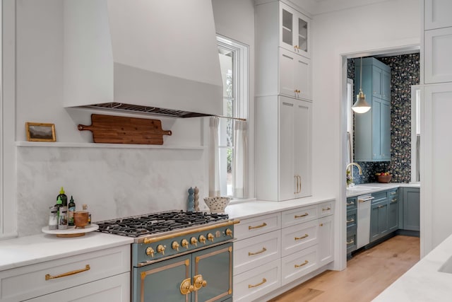 kitchen featuring wall chimney exhaust hood, white cabinetry, tasteful backsplash, light hardwood / wood-style flooring, and stove