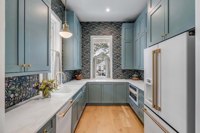 kitchen with sink, hanging light fixtures, white appliances, light hardwood / wood-style floors, and decorative backsplash