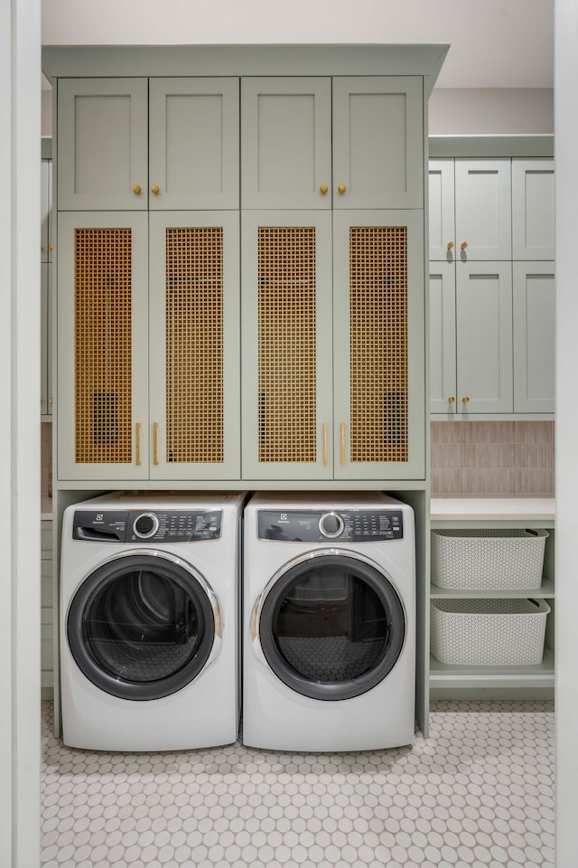 clothes washing area featuring separate washer and dryer, cabinets, and light tile patterned flooring