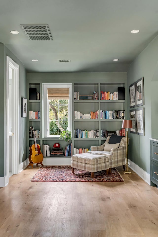 living area with built in features and light wood-type flooring