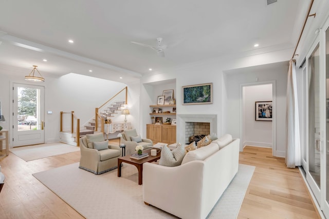 living room featuring light hardwood / wood-style flooring, ornamental molding, and ceiling fan