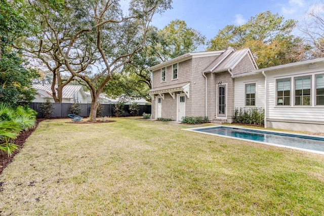 back of house featuring a fenced in pool and a lawn