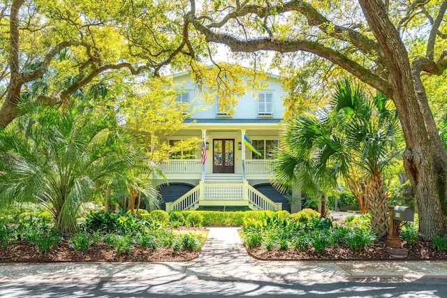 view of front of home with covered porch, french doors, and stairs