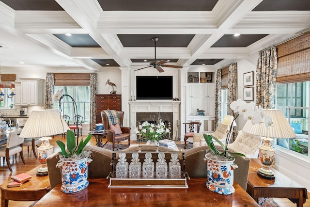 living area with a premium fireplace, ornamental molding, ceiling fan, coffered ceiling, and beamed ceiling