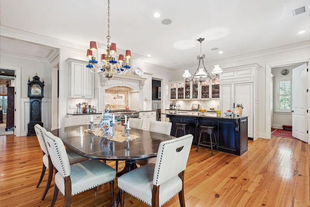 dining room featuring light wood finished floors, visible vents, a chandelier, and crown molding