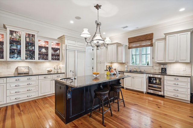 kitchen with wine cooler, a sink, light wood-type flooring, a kitchen bar, and crown molding