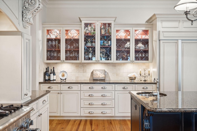 kitchen featuring backsplash, dark stone countertops, a sink, and crown molding