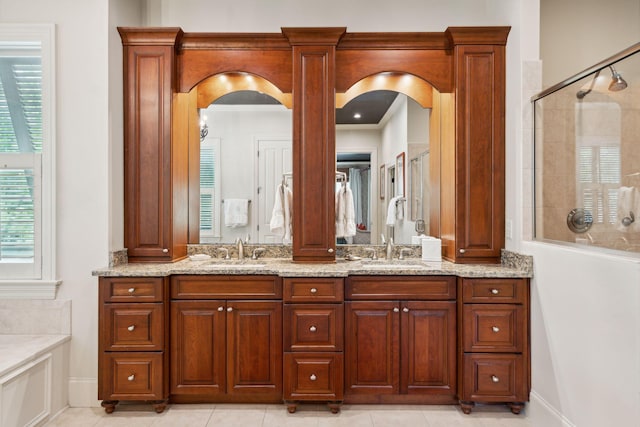 bathroom featuring double vanity, tiled shower, and a sink