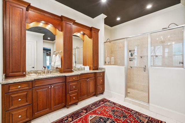 bathroom with tile patterned flooring, vanity, baseboards, a shower stall, and crown molding