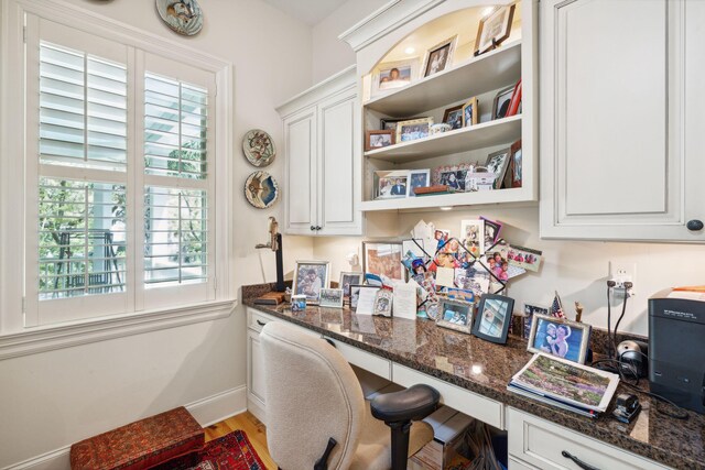 office space featuring baseboards, built in desk, and wood finished floors