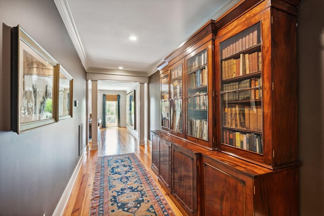 corridor with baseboards, light wood-style flooring, crown molding, ornate columns, and recessed lighting