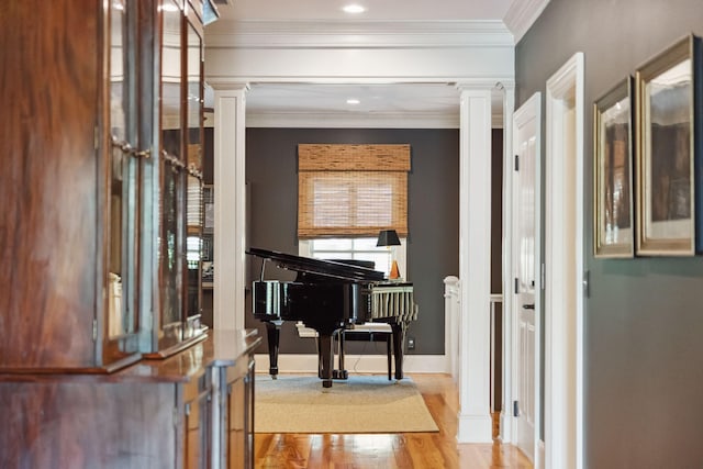 hallway with ornamental molding, baseboards, ornate columns, and wood finished floors